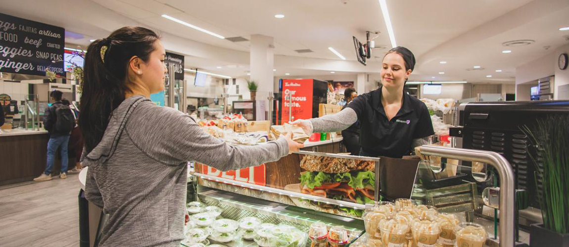 Server handing over good to a student in dining hall