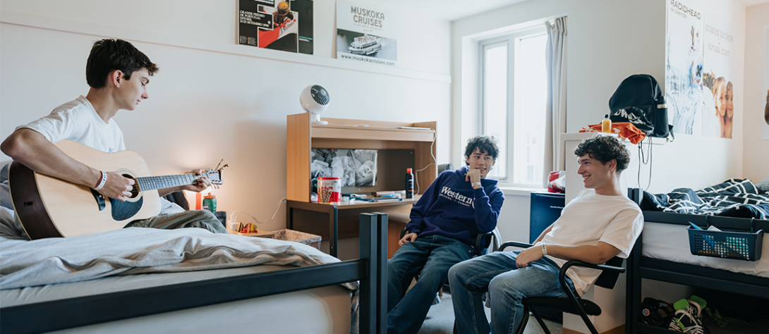 Three students sitting around their bedroom